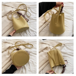 Detail of yellow lychee leather bucket bag with silk scarf handle and round base