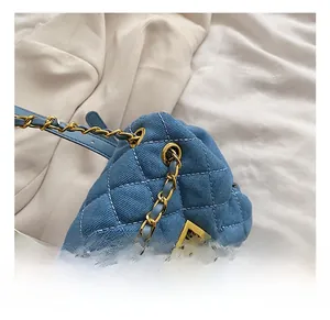 Detail of blue quilted denim backpack featuring gold chain strap and metal swivel lock