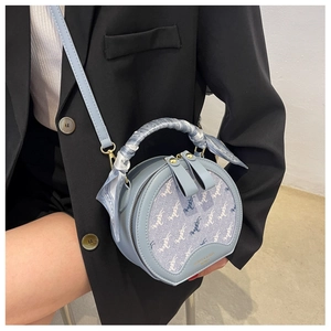 Detail of light blue round crossbody bag with animal print and silk scarf handle