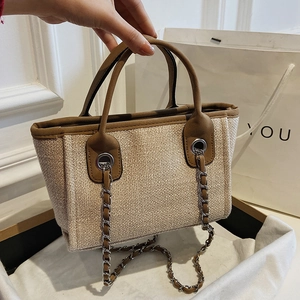 Beige woven bucket bag with brown leather trim and metal chain strap for women