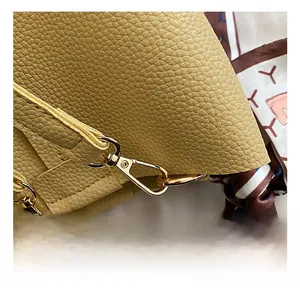 Detailed macro of yellow lychee leather bag with gold hardware and patterned silk scarf