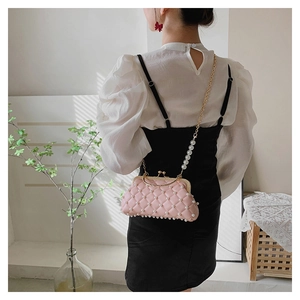 Détail du sac à main matelassé rose avec perles et bandoulière en chaîne sur un modèle
