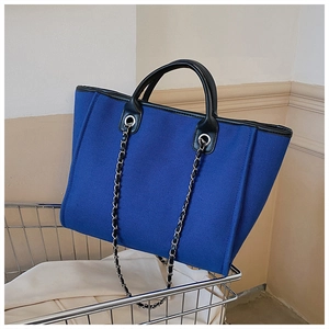 Detail of royal blue tote bag with metallic chain strap hanging on a cart