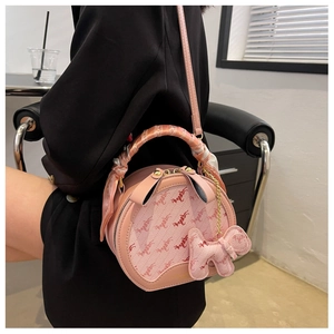 Detail of pink round shoulder bag with silk scarf handle and cute elephant charm