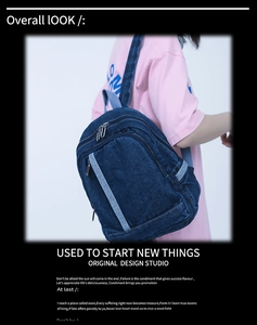 Detail view of washed denim backpack featuring front pocket and silver metal zippers