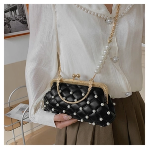 Détail du sac de soirée matelassé noir avec accents de perles blanches et cadre doré