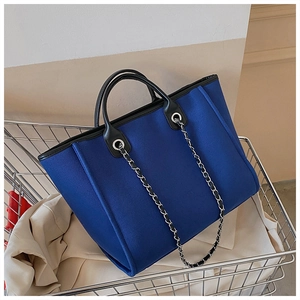 Detail of blue nylon tote bag with black leather trim and silver chain in shopping cart