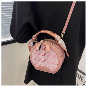 Detail of pink round crossbody bag featuring horse pattern fabric and scarf-wrapped handle