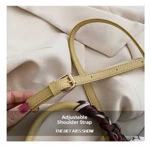 Detail of adjustable yellow lychee leather strap with gold buckle and silk scarf handle