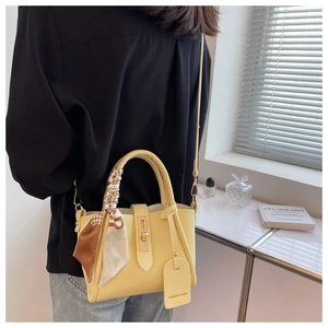 Yellow leather tote bag with silk scarf detail and turn-lock closure on model