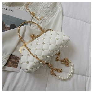 Détail du sac à main blanc matelassé avec ornements en perles et poignée dorée