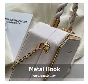 Detail of light pink hexagonal leather bag with gold metal hooks and braided handle
