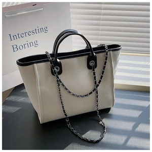Detail of contrast stitch tote bag with chain strap and dual-tone canvas texture
