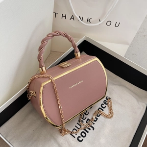 Pink leather handbag with woven handle and gold chain strap in a white gift box