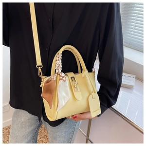 Detail of light yellow tote bag with textured leather and scarf-wrapped handle