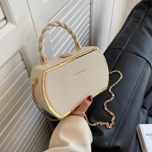 Chic cream white handbag with gold chain strap and twisted handle in a modern setting