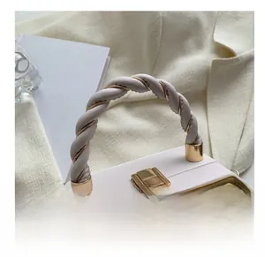 Detail of cream white leather handbag featuring woven handle and gold metal lock buckle
