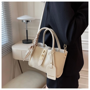 Detail of cream lychee leather bucket bag with gold hardware and silk scarf handle