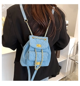 Detail of light blue quilted denim backpack with gold chain straps on a model