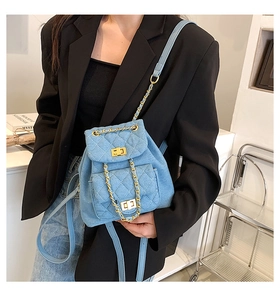 Detail of light blue quilted denim mini backpack with gold chain straps on a model
