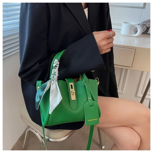 Detail of green pebble leather tote with gold hardware and silk scarf handle