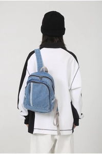 Close-up of minimalist blue washed denim backpack with gray straps on model's back