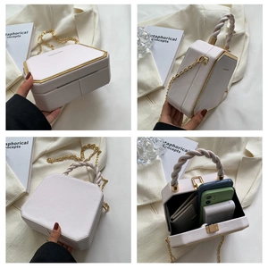Detail view of white leather hexagonal box bag with chain strap and braided handle