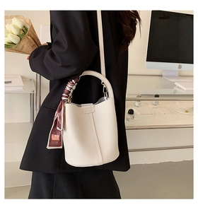 Close-up of cream lychee texture leather bucket bag with elegant floral scarf handle