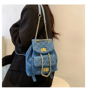 Close-up of quilted blue denim mini backpack with gold chain straps and double gold locks