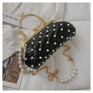 Détail d'un sac à main matelassé noir avec perles blanches et fermoir doré