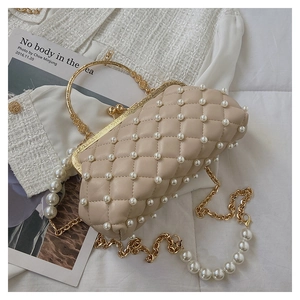 Détail d'un sac de soirée matelassé beige avec perles et poignée en métal doré