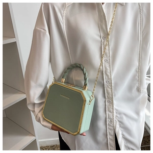 Detail of light green octagonal hard shell bag with braided handle and gold chain