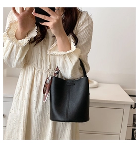 Detail of black lychee grain leather bucket bag with decorative colorful geometric silk scarf