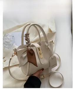 Detailed close-up of a white lychee grain leather tote bag with silk scarf and gold lock