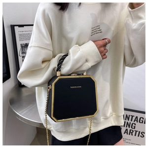 Detail of black octagonal bag featuring gold metal trim and chain shoulder strap