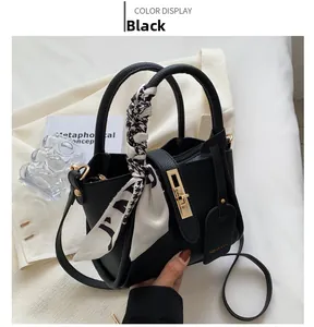 Detail of black pebbled leather tote with gold twist lock and printed silk scarf handle