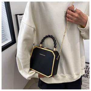 Detail of a black geometric crossbody bag with gold metal trim and chain strap