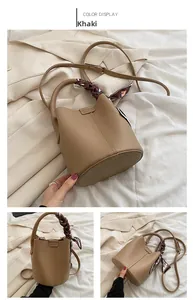 Detail of khaki lychee grain leather bucket bag with silk scarf handle and strap