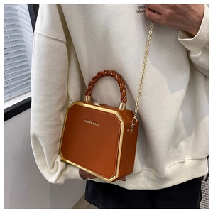 Detail of vintage brown box bag featuring a twisted handle and gold chain strap