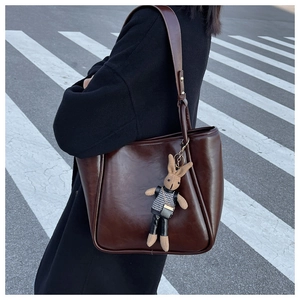 Détail d'un grand sac cabas marron vintage avec porte-clés lapin sur fond de rue