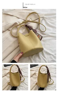 Detail of yellow lychee leather bucket bag with decorative silk scarf and thin strap