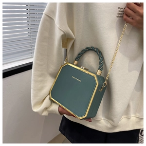 Close-up of a dark green octagonal handbag with gold chain and matte leather texture