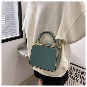 Detail of dark green octagonal crossbody bag with gold metal trim and chain strap