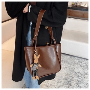 Gros plan sur un sac cabas en cuir marron orné d'un joli porte-clés lapin en tricot