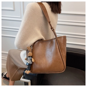 Vue détaillée du sac cabas en cuir marron avec charme de lapin sur un pull beige