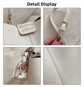 Detail view of lychee grain leather, gold hardware, and silk scarf on the white handbag