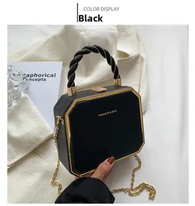 Detail of black octagonal box bag with gold metal trim and textured leather finish