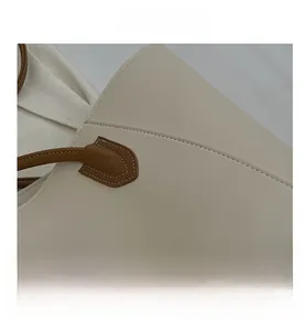 Close-up of reinforced stitching and brown leather handle on the beige tote bag