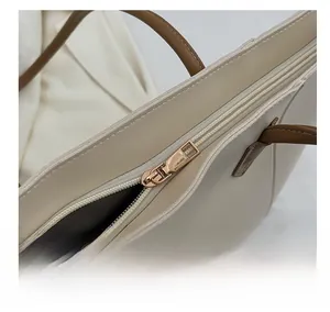 Detailed close-up of the smooth gold-tone zipper and stitching on the tote bag