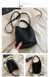 Detail of black pebbled bucket bag with decorative scarf handle and adjustable strap